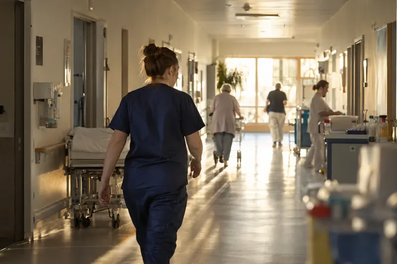 Eine Pflegefachkraft geht über einen hellen Klinikflur